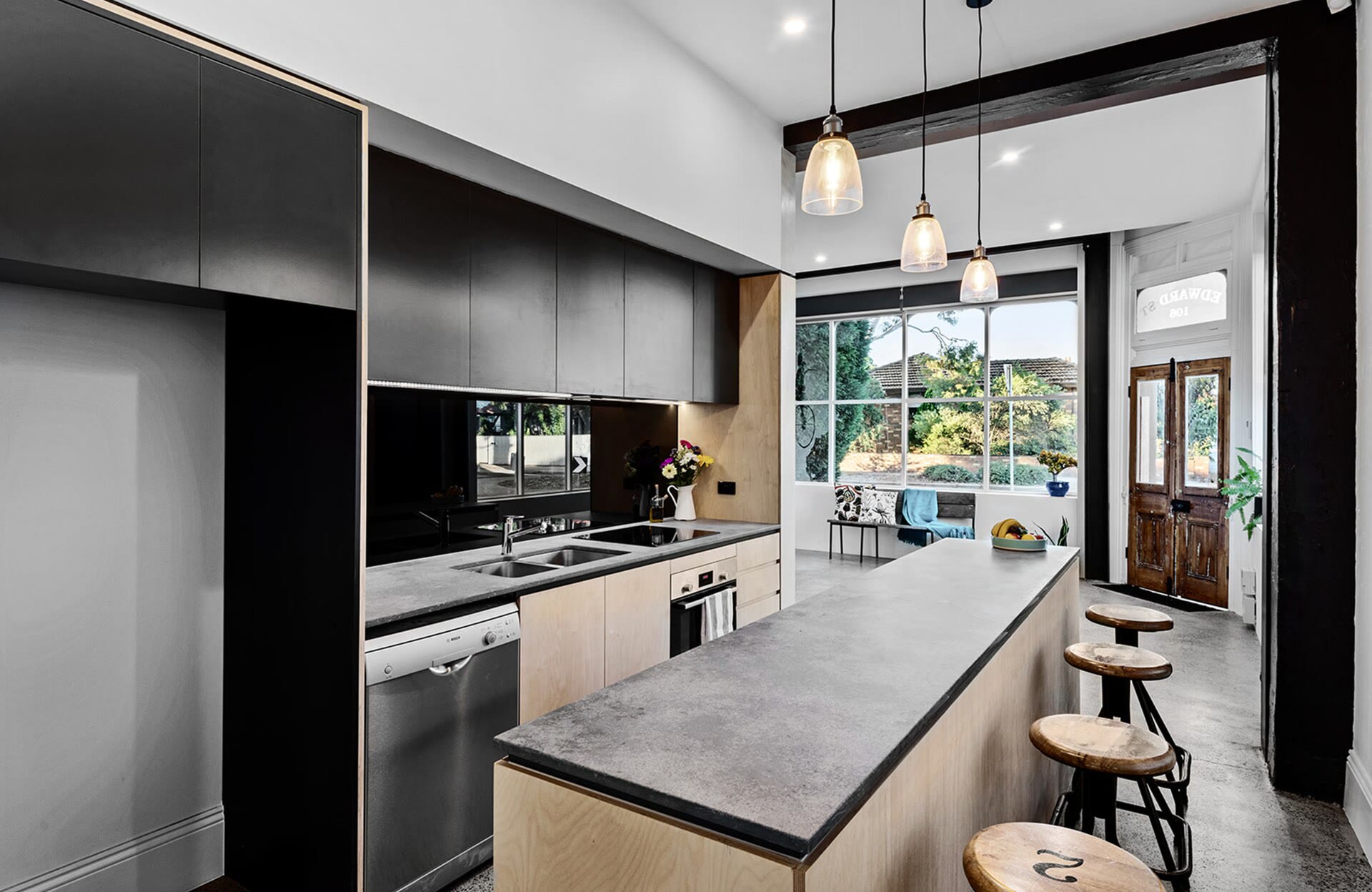 Renovated kitchen with black cabinetry and a concrete-look island bench